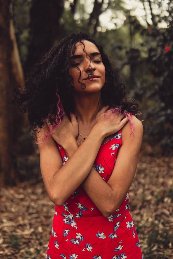 A woman in a floral red dress stands confidently in a lush São Paulo forest.