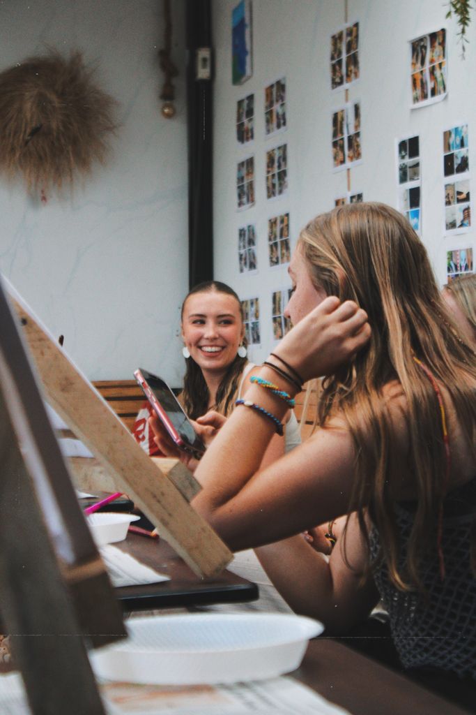 Teens immersed in a creative art workshop, laughing and painting indoors.