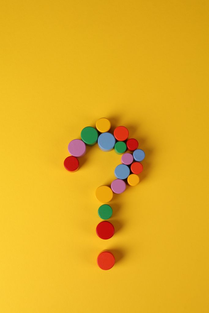 Vibrant image of colored wooden blocks arranged as a question mark on a yellow background.